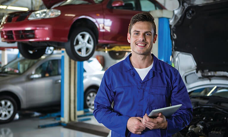 Mechanic in front of lifted car using tablet