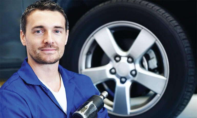 Mechanic standing in front of a tire with pneumatic tool