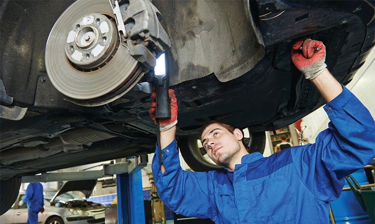 A Ford mechanic adjusting a car's brakes